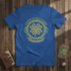 Blue t-shirt with "Good Luck Charm" text and a golden four-leaf clover design bordered by Celtic knots and green sparkles