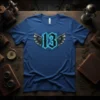 Blue t-shirt with the number 13 in gothic font, flanked by detailed steampunk wings with glowing blue outlines and cracked