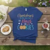 Grandmas NEVER RUN OUT OF Hugs OR COOKIES text design on a navy blue t-shirt, featuring colorful typography and cookie