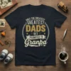 Only The Greatest Dads Get Promoted To Granpa text design on a navy t-shirt, featuring distressed typography and a circular