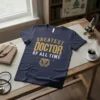 Greatest Doctor Of All Time text design with medical caduceus symbol on a navy t-shirt