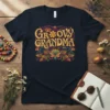 Groovy Grandma text design with retro boho floral accents in gold, purple, teal, and orange on a navy t-shirt