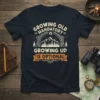 Growing Old Is Mandatory Growing Up Is Optional quote on a navy t-shirt with mountain and forest graphic