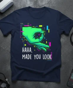 T-shirt with "HAHA, MADE YOU LOOK" text and a green hand making the circle game symbol, set against a glitch