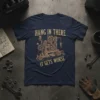Navy blue t-shirt with "Hang In There It Gets Worse" text and a complex mechanical contraption graphic in gold