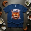 Hangry Cat T-Shirt featuring a grumpy orange cat with bright blue eyes, text "HANGRY" above, and icons for food and