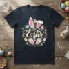 Happy Easter text with bunny ears, paws, and floral Easter egg design on a dark t-shirt