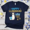Happy Llamakkah text with a llama wearing sunglasses next to a menorah and Star of David on a navy t-shirt