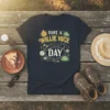 Dark t-shirt with "Have A Willie Nice Day" text, featuring a smiling sun, banjo, musical notes, and frogs