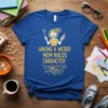 Blue t-shirt with yellow text "Having A Weird Mom Builds Character" and a cartoon illustration of a smiling mom holding
