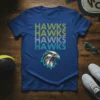 Bold repeating text "HAWKS HAWKS HAWKS HAWKS" with a geometric eagle head graphic on a blue t-shirt