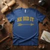 Blue t-shirt with yellow glitter text "HE DID IT" and an arrow graphic