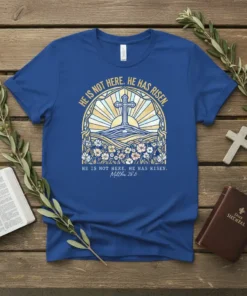Blue t-shirt with "HE IS NOT HERE. HE HAS RISEN. Matthew 28:6" text and sunrise cross graphic