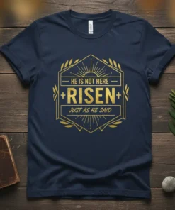 Navy blue t-shirt with gold text "HE IS NOT HERE RISEN JUST AS HE SAID" in a hexagonal design, featuring