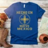 Hecho en Nuevo Mexico t-shirt with Zia symbol in gold, royal blue shirt, representing New Mexico pride