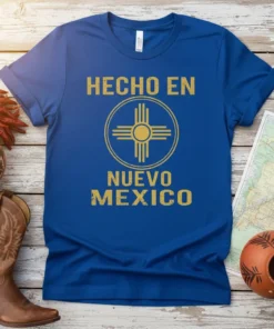 Hecho en Nuevo Mexico t-shirt with Zia symbol in gold, royal blue shirt, representing New Mexico pride