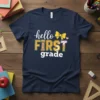 Navy t-shirt with "hello FIRST grade" text, featuring a yellow bow, pencil graphic, and colorful stripes