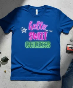 Blue t-shirt with neon pink and green text reading "hello SWEET CHEEKS", featuring stars and eyelashes graphics