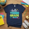 Navy t-shirt with "hello THIRD GRADE" text in colorful fonts, featuring a pencil graphic and confetti