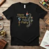 Black t-shirt with gold text "Here Fishy Fishy Fishy" and watercolor fishing lures and bobber graphic