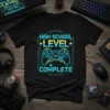 Black t-shirt with "High School Level Complete" text and a neon blue and yellow video game controller graphic