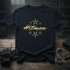 Black t-shirt featuring the golden "Hitman" text logo surrounded by star graphics, representing gaming and stealth