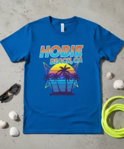 Retro sunset graphic with palm trees and "HOBIE BEACH, CA" text on a blue t-shirt