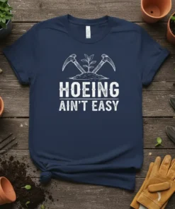 Hoeing Ain't Easy quote with crossed garden tools and a seedling graphic on a navy blue t-shirt