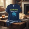 Navy blue t-shirt with yellow and blue text "Hold my drink I gotta pet this dog" and a neon paw