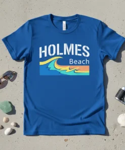 Blue t-shirt with white "HOLMES" text above a colorful wave graphic and "Beach" text, representing Holmes Beach vacation