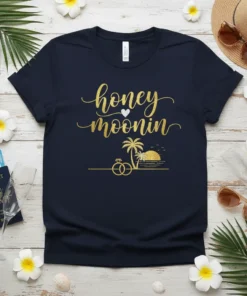 Navy t-shirt with "honey moonin" in gold glitter text and a tropical beach graphic with palm trees and wedding rings