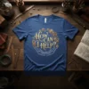 Steampunk gears surrounding the phrase "How Can I Help?" with cupped hands below on a blue t-shirt