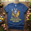 Blue t-shirt with yellow text "How Easter Eggs Are Made" above a cartoon bunny riding a chicken on an egg
