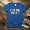 Blue t-shirt with "HOW YOU DOIN'?" text in vintage font and three colored circles below, inspired by Friends TV show