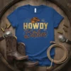 Blue t-shirt with "HOWDY Bitches" text in gold and rope design, featuring a cowboy hat graphic