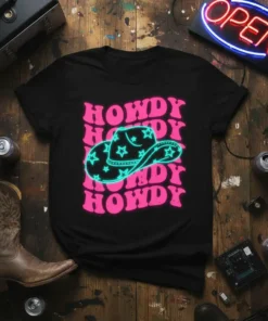 Black t-shirt with repeated pink "HOWDY" text and a central neon turquoise cowboy hat with stars graphic