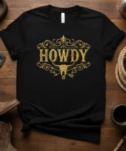 Black t-shirt with distressed gold "Howdy" text and a bull skull graphic, perfect for western wear enthusiasts