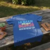 Blue t-shirt with neon-style text "HUMAN 100% organic BEINGS COLOR AND SIZE MAY VARY" graphic