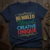HUMBLED Blessed CREATIVE UNIQUE text design in gold, green, blue, and red on a navy t-shirt