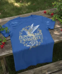 Hummingbird Whisperer graphic t-shirt with a golden hummingbird and floral wreath design
