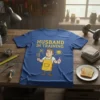 Husband In Training text with cartoon man holding a baby bottle and frying pan on a blue t-shirt