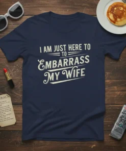 Navy blue t-shirt with distressed white text "I AM JUST HERE TO EMBARRASS MY WIFE" in a playful font