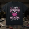 I AM NOT SPOILED MY MECHANIC just loves me text with crossed wrenches and pink paint splatters on a black