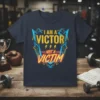 I Am A Victor Not A Victim quote t-shirt with bold yellow and blue graphic design, featuring lightning bolt accents