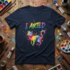 I ARTED text above a colorful geometric cat design on a navy blue t-shirt, art supplies background
