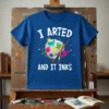 Blue t-shirt with white text "I ARTED AND IT INKS" and a colorful art palette with brushes