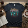 I believe IN THE POWER OF YET quote on a dark t-shirt with gold and teal lettering and a circular