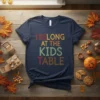 I Belong At The Kids Table text design in colorful, retro font on a navy t-shirt, with a Thanksgiving theme