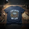I Can't Believe This My Life quote in steampunk font with gear graphics on a navy t-shirt