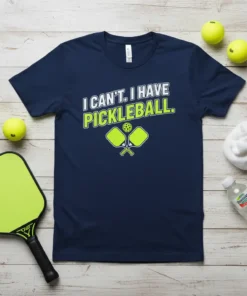 Navy t-shirt with white and lime green text "I CAN'T. I HAVE PICKLEBALL." and graphic of pickleball paddles and ball